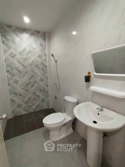 Modern bathroom with sleek design, featuring a shower, toilet, and sink in a bright, tiled space.