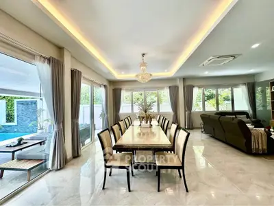 Luxurious open-plan living and dining area with elegant chandelier and pool view, perfect for entertaining.
