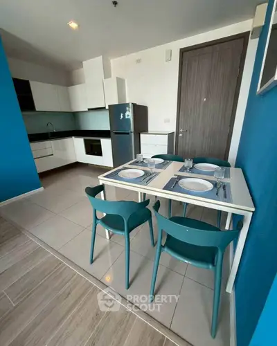 Modern kitchen with dining area, featuring sleek cabinetry and stylish blue accents.