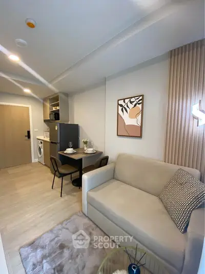 Modern living room with open kitchen, cozy sofa, and stylish decor in a compact apartment.