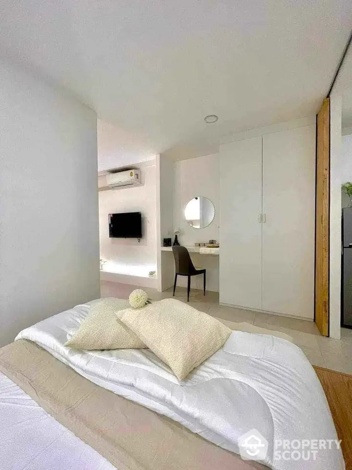 Modern bedroom with minimalist decor and built-in wardrobe, featuring a cozy bed and wall-mounted TV.