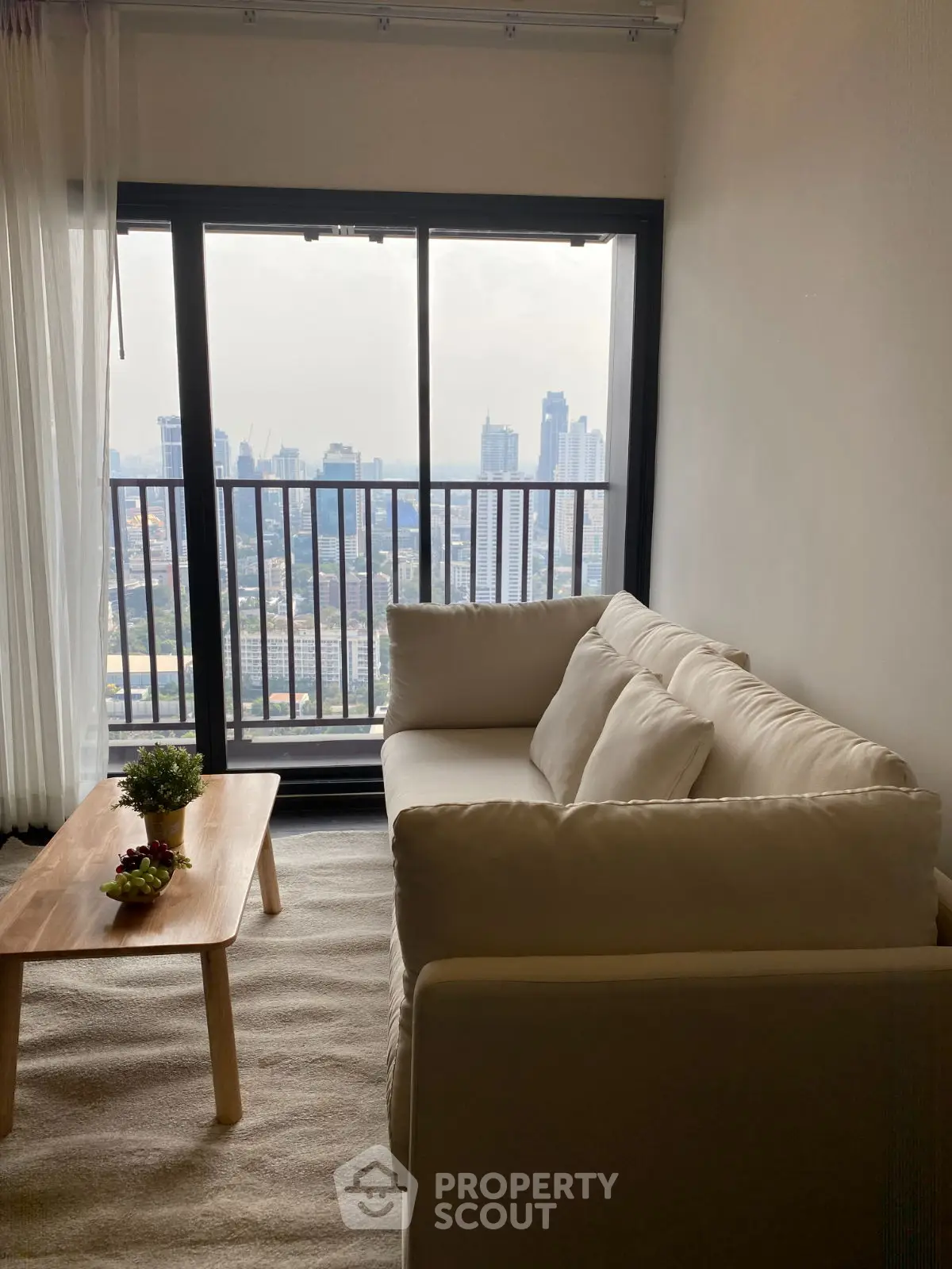 Modern living room with cozy sofa and stunning city view from large window.
