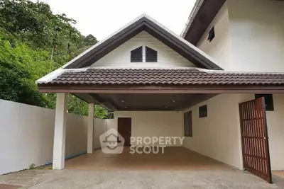 Charming house with spacious carport and lush greenery, perfect for serene living.