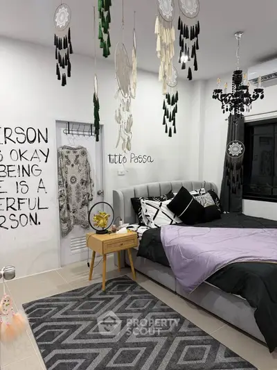 Stylish bedroom with modern decor and dreamcatchers, featuring a cozy bed and chic chandelier.