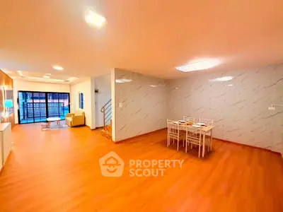 Spacious open-plan living and dining area with modern lighting and wooden flooring.