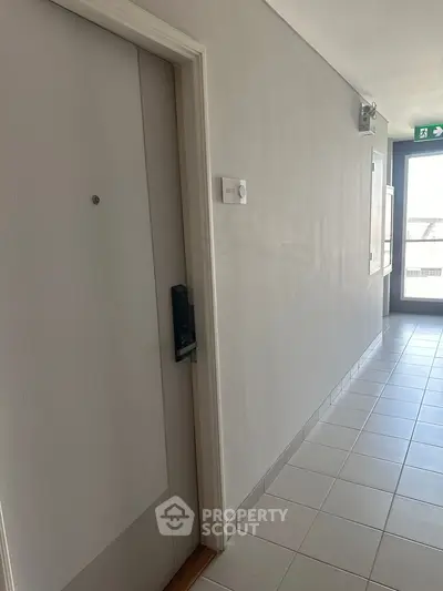 Modern apartment hallway with secure entry door and bright natural lighting.