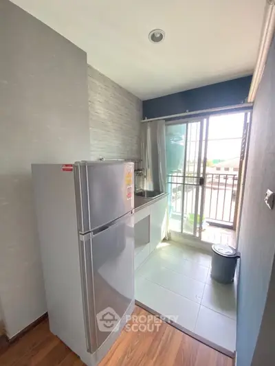 Modern kitchen with sleek fridge and balcony view, perfect for urban living.