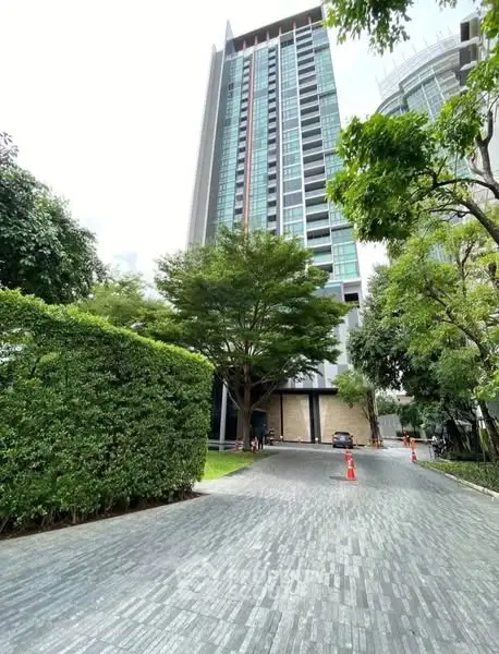 Modern high-rise building with lush greenery and paved driveway