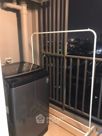 High-rise balcony with washing machine and city night view, perfect for urban living convenience.