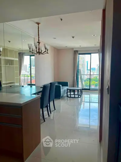 Spacious living room with elegant chandelier and city view balcony in modern apartment.