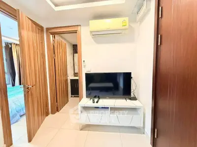 Modern apartment interior with TV, air conditioning, and wooden doors.