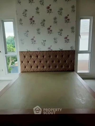 Spacious bedroom with elegant floral wallpaper and large windows offering natural light.