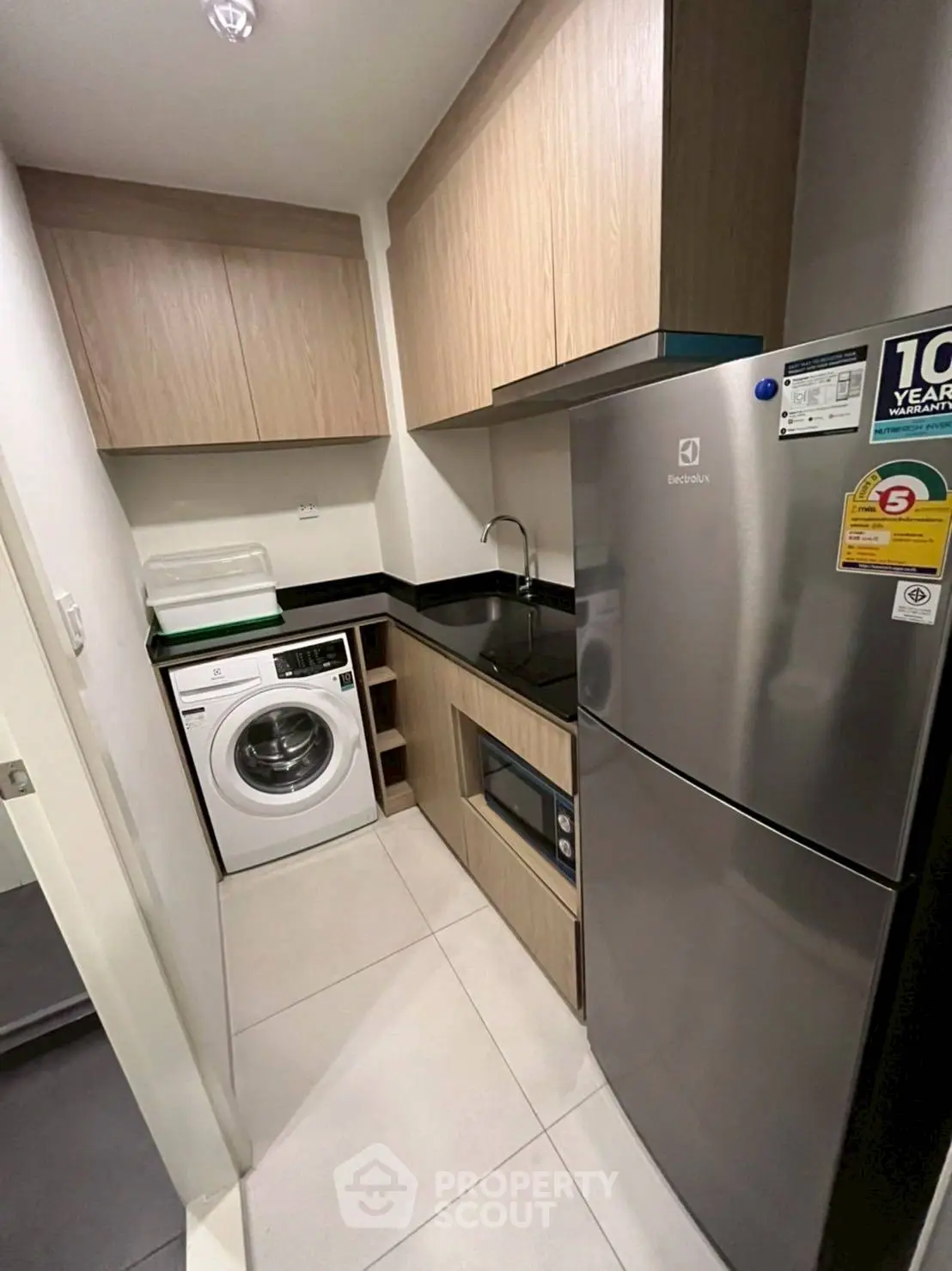 Modern compact kitchen with washing machine and fridge in sleek apartment