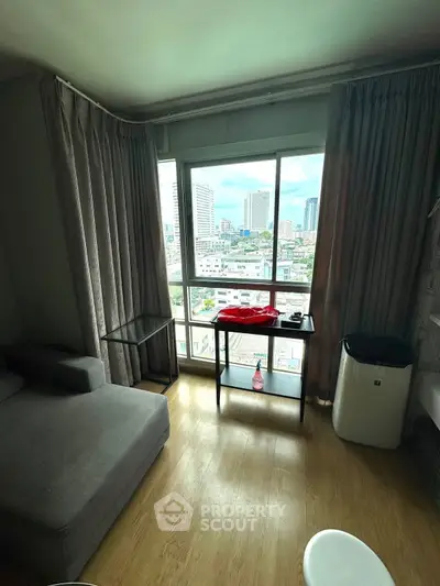 Cozy living room with city view, featuring modern furniture and large windows for natural light.