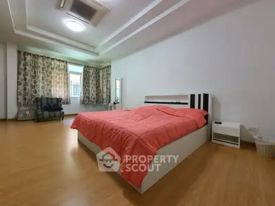 Spacious bedroom with modern decor and large windows for natural light.