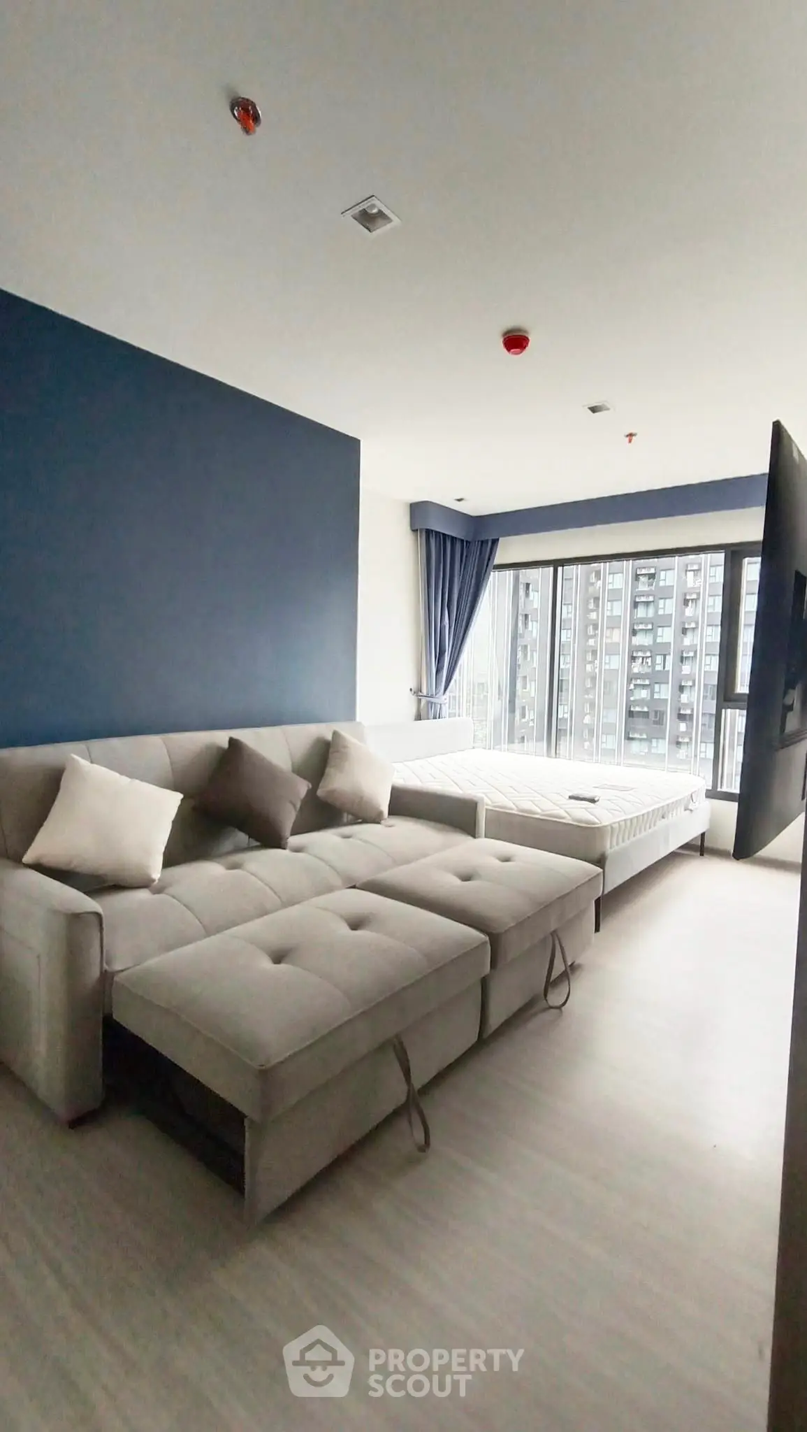 Modern living room with stylish sofa and large windows offering city views