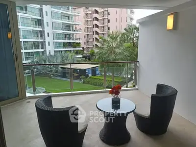 Spacious balcony with modern furniture overlooking lush garden and contemporary buildings.