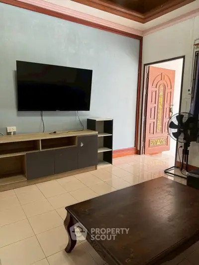 Spacious living room with modern TV setup and elegant wooden door