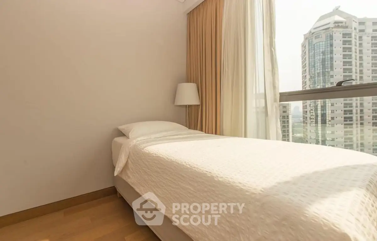 Cozy bedroom with single bed and city view, perfect for urban living.