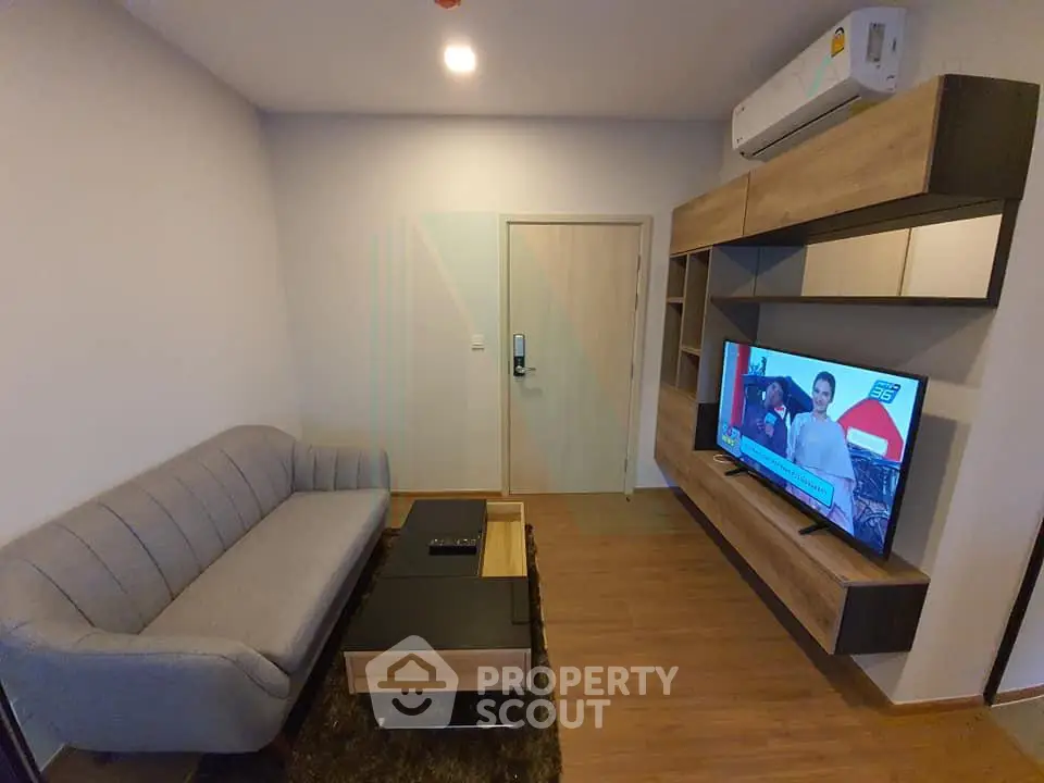Modern living room with stylish furniture and wall-mounted TV in a cozy apartment.