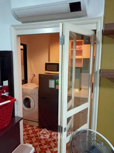 Compact kitchen with washing machine and microwave in cozy apartment