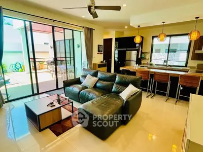 Spacious open-plan living room with modern kitchen and patio access, perfect for entertaining.