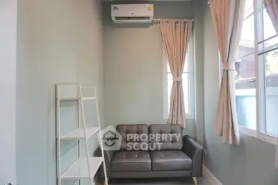 Cozy and modern living room with comfortable grey sofa, elegant curtains, and a sleek white shelving unit under a well-placed air conditioner.