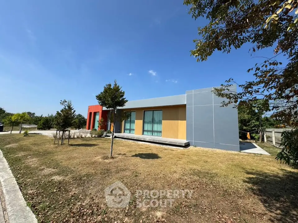 Modern single-story home with colorful facade and spacious lawn under clear blue sky.
