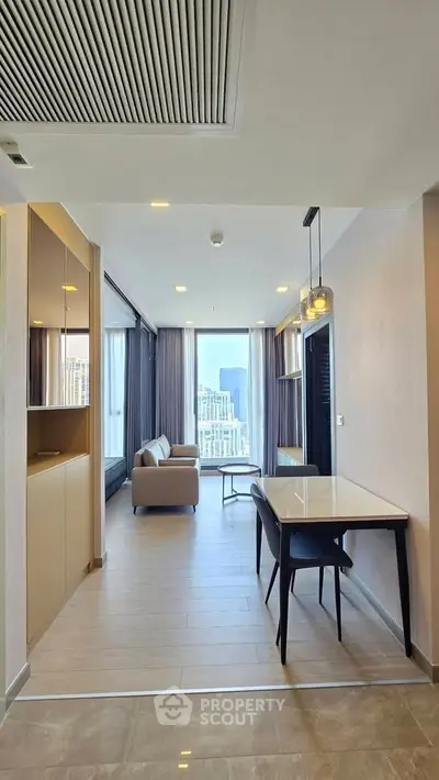 Modern apartment interior with open layout, featuring a cozy living area and dining space with city view.
