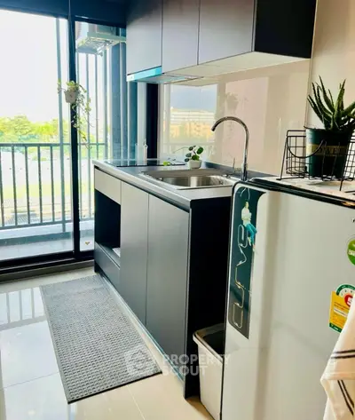 Modern kitchen with sleek cabinetry and balcony view, perfect for urban living.