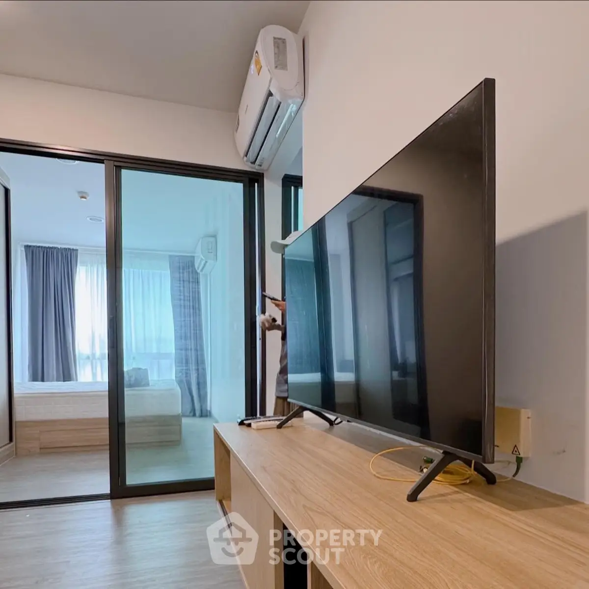 Modern living room with sleek TV and view into a stylish bedroom