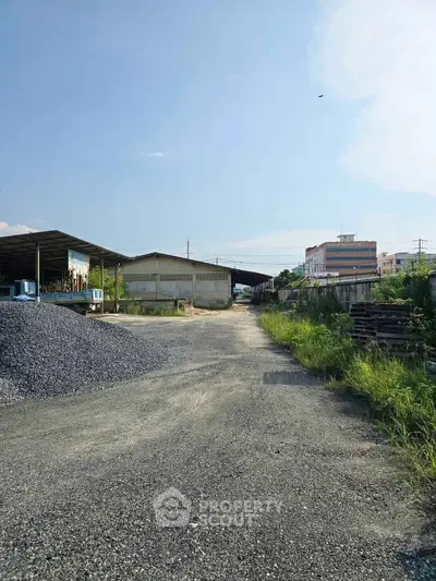 Expansive industrial property with warehouses and open gravel area, ideal for commercial use.