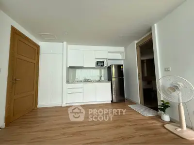 Modern kitchen with sleek white cabinets and stainless steel appliances in a cozy apartment.