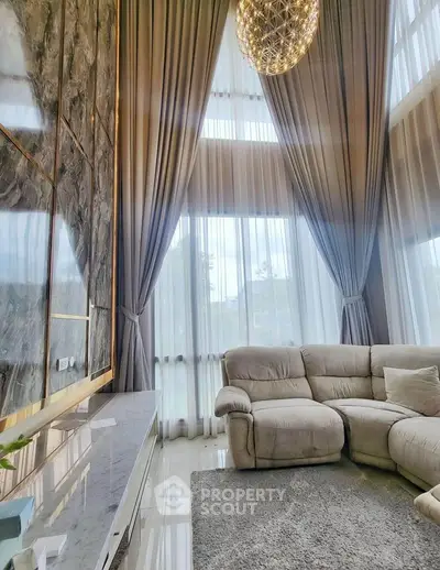 Luxurious living room with high ceilings, elegant curtains, and plush seating in a modern home.