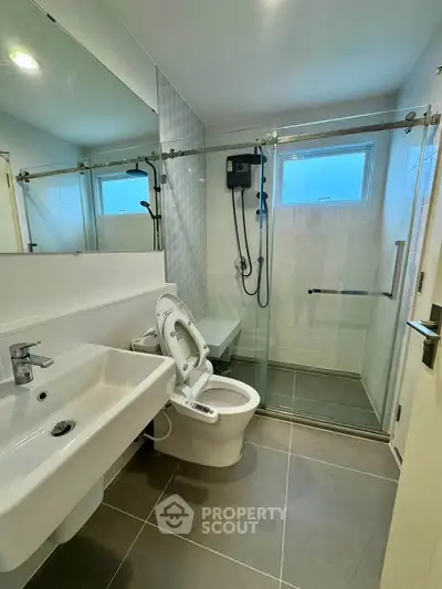 Modern bathroom with sleek fixtures and glass shower enclosure in a contemporary apartment.