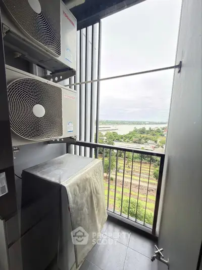 Compact balcony with air conditioning units and scenic view of greenery and river.