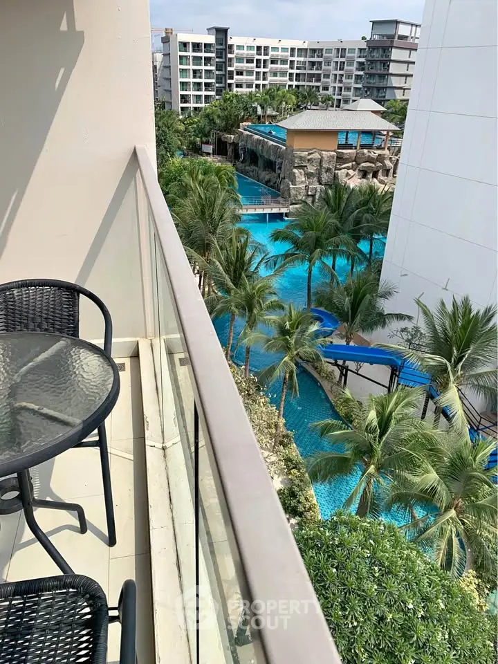 Stunning balcony view overlooking a luxurious pool and lush tropical landscape.
