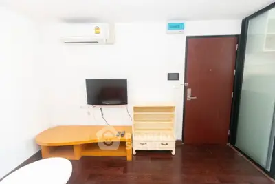 Modern apartment interior with TV, air conditioning, and wooden furniture.
