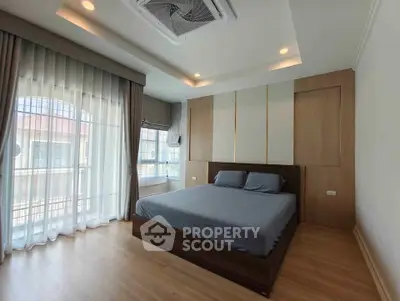 Spacious modern bedroom with large windows and elegant wooden flooring.