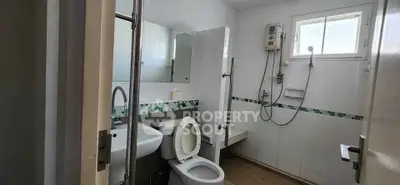 Modern bathroom with shower, toilet, and sink in a bright, tiled space.