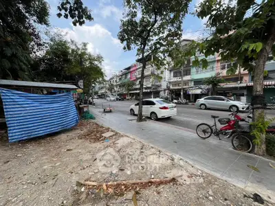 Street view of urban area with parked cars and bicycles, showcasing potential real estate development.