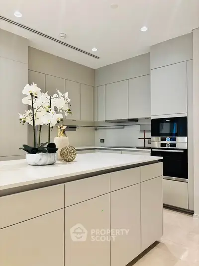 Modern kitchen with sleek cabinetry and built-in appliances, featuring elegant decor and bright lighting.