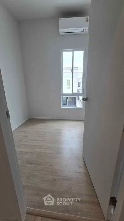 Bright empty room with wooden flooring and air conditioning, perfect for customization.