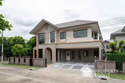 Modern two-story house with spacious driveway and lush greenery in suburban neighborhood.