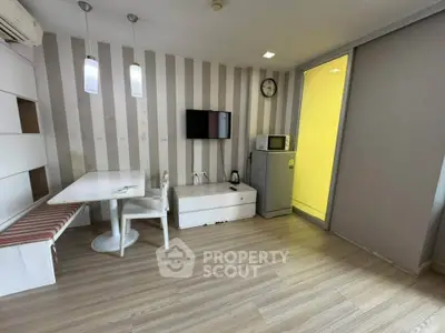 Modern living room with stylish decor, wall-mounted TV, and compact dining area.