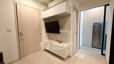 Modern apartment interior with sleek TV setup and compact kitchen area.