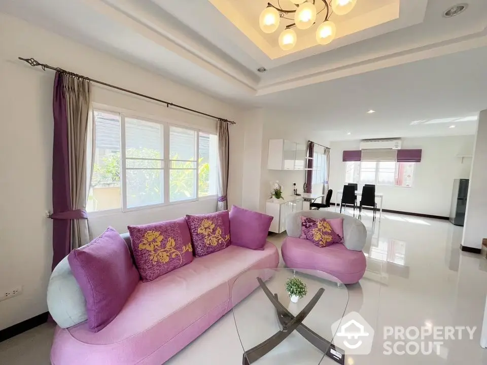 Spacious and bright living room with glossy white tiles and vibrant pink sofas, leading to an elegant dining area with modern lighting.