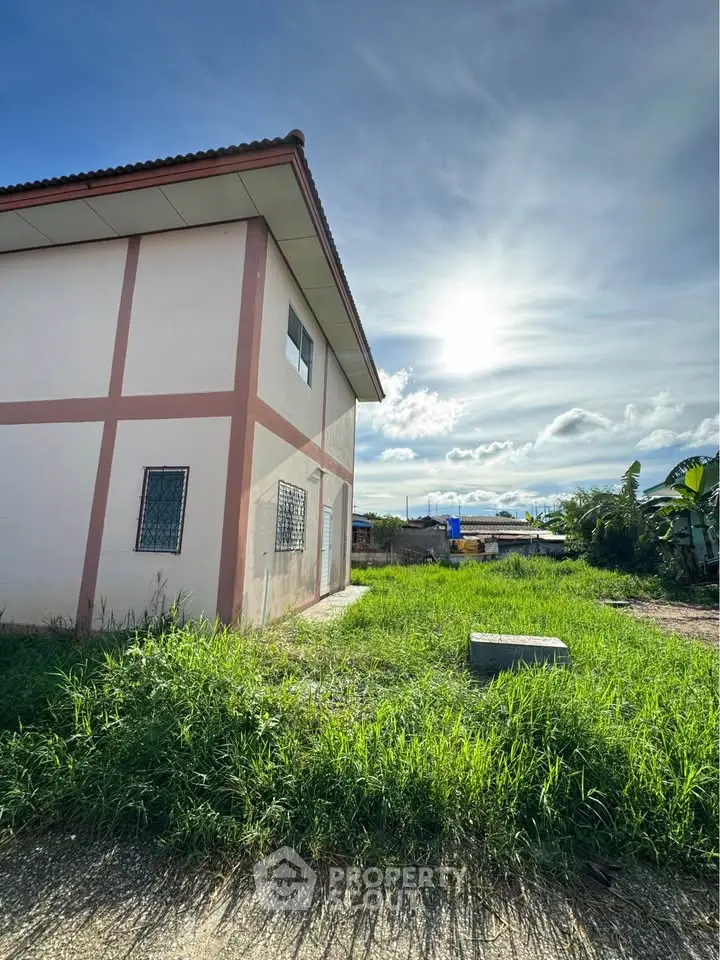 Charming suburban house with spacious green lawn under a bright sunny sky, perfect for family living.