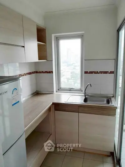 Modern compact kitchen with city view, featuring sleek cabinetry and a large window.