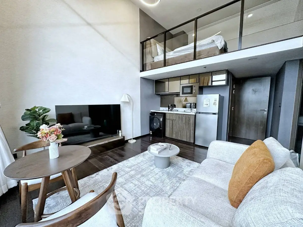 Modern loft apartment with open living area and mezzanine bedroom, featuring sleek kitchen and stylish decor.